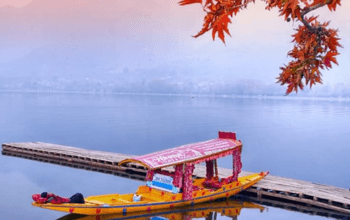 Serene Dal Lake in Srinagar, Kashmir, with houseboats and Himalayan mountains in the background.