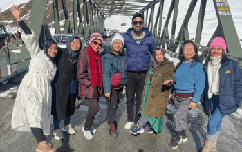 Group of travelers enjoying a shikara ride on Dal Lake with Kashmir’s mountains in the background.