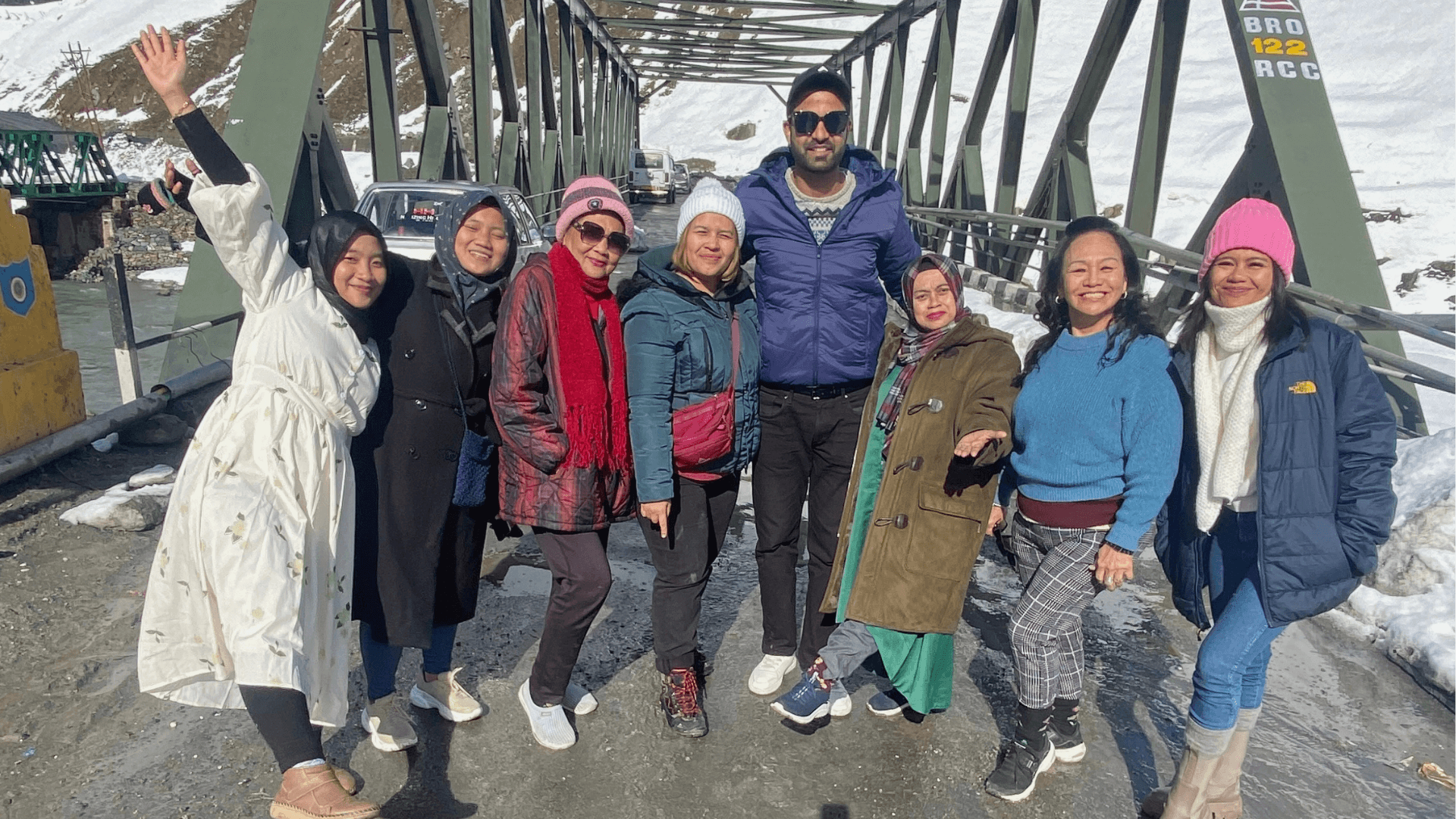 Group of travelers enjoying a shikara ride on Dal Lake with Kashmir’s mountains in the background.