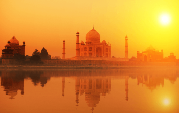 Aerial view of the Taj Mahal with its white marble dome and minarets, surrounded by lush gardens.